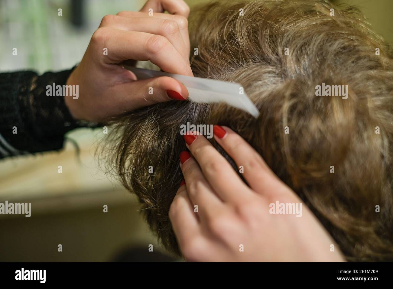 Hair dresser girl while applying hair dye to a white haired elderly woman customer at work,home beauty treatment Stock Photo