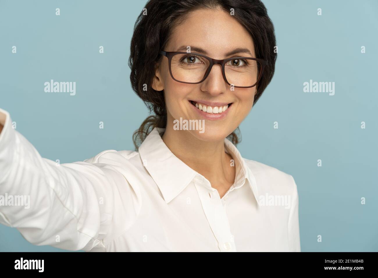 Woman having cheerful expression making selfie, stretching arm to camera, photographing herself Stock Photo
