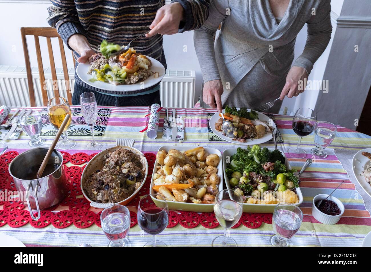 Members of a British family help themselves to a turkey and vegetables Christmas Day lunch, on 25th December 2020 in London, England. Stock Photo