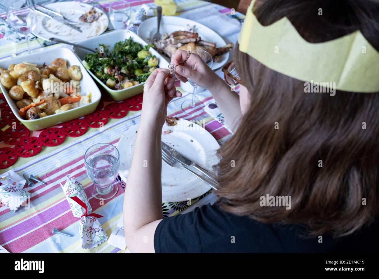 A young woman tries to solve a cracker novelty puzzle after a family lunch on Christmas Day, on 25th December 2020 in London, England. Stock Photo