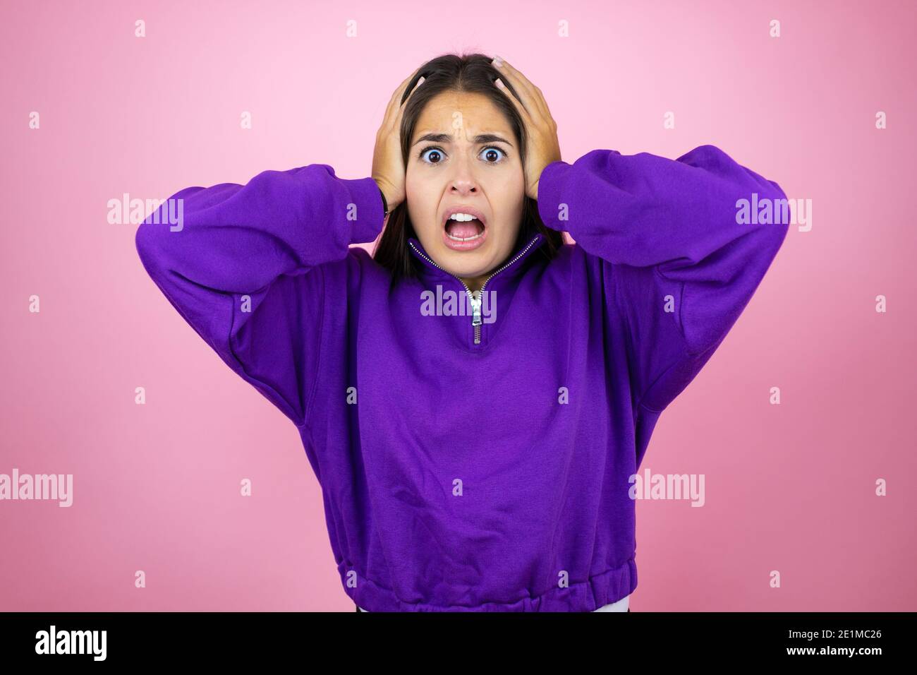 Pink Scared Young beautiful woman wearing sweatshirt over isolated pink background ...