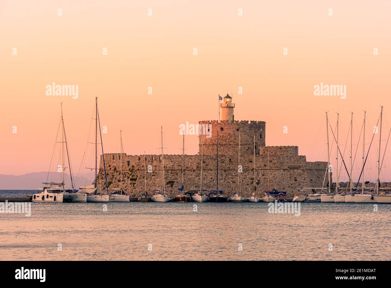 Greek Island sunset over St Nicholas Fortress, Mandraki harbour, Rhodes Town, Rhodes Island, Greece Stock Photo