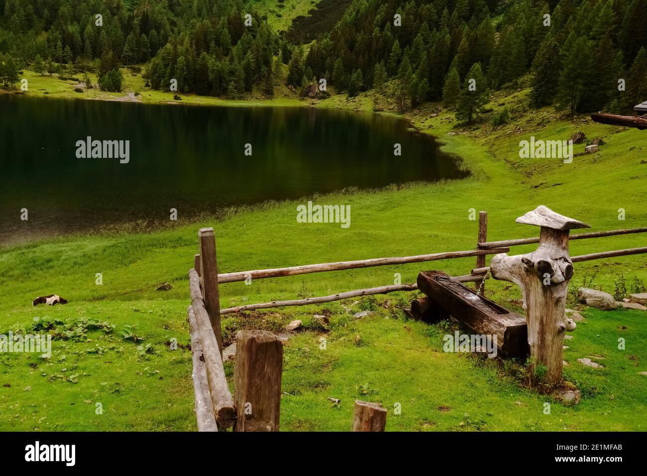 wooden fountain and fence in a green valley with a lake while hiking ...