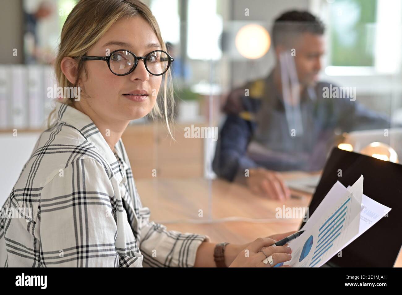 Office worker with eyeglasses working in open space area protected with plexiglas Stock Photo