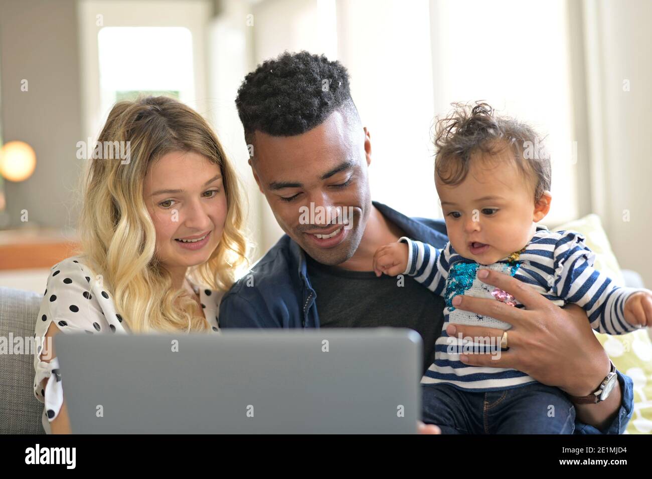 Parents with baby girl using laptop computer at home Stock Photo