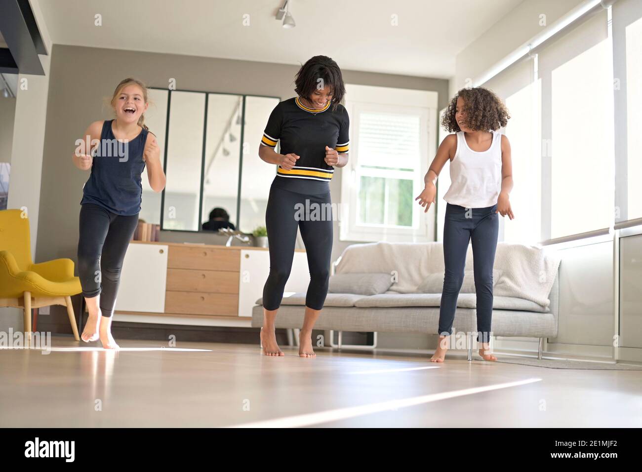 Woman with girls doing fitness exercices at home Stock Photo