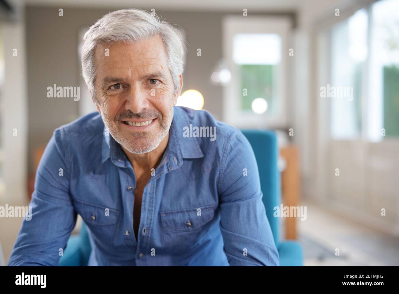 Portrait Of 60 Year Old Man With Grey Hair And Blue Shirt Looking At