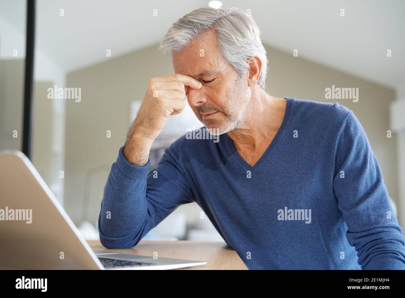 Senior man having a headache while working on laptop computer Stock Photo