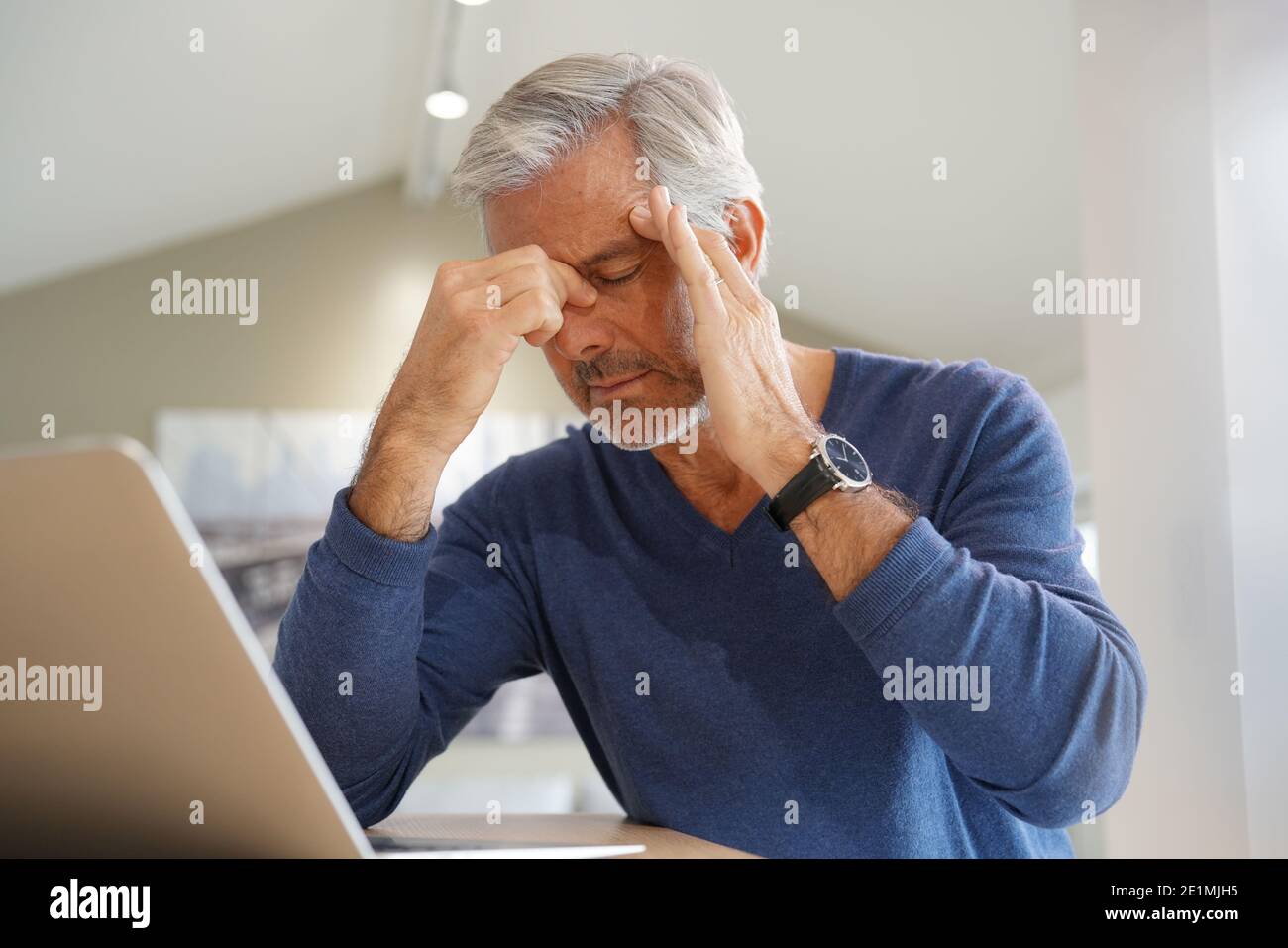 Senior man having a headache while working on laptop computer Stock Photo