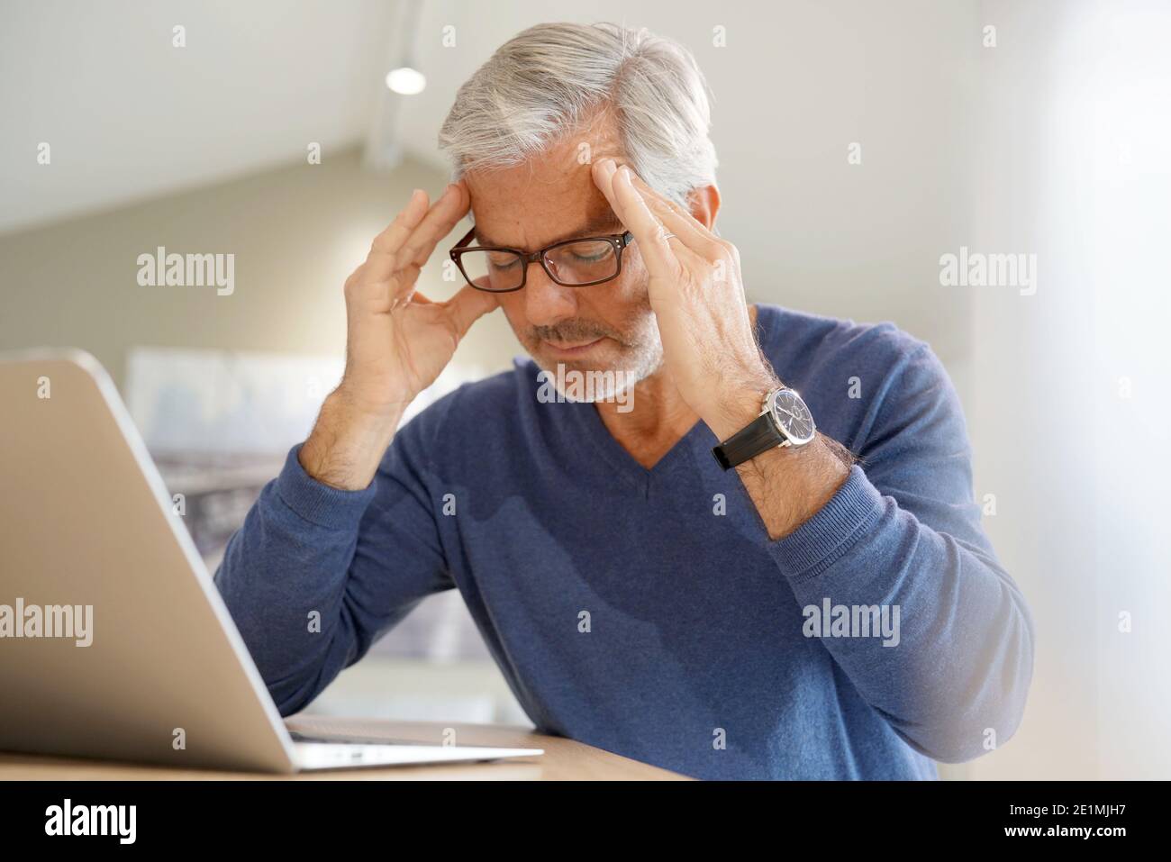 Senior man having migraine while working on laptop computer Stock Photo