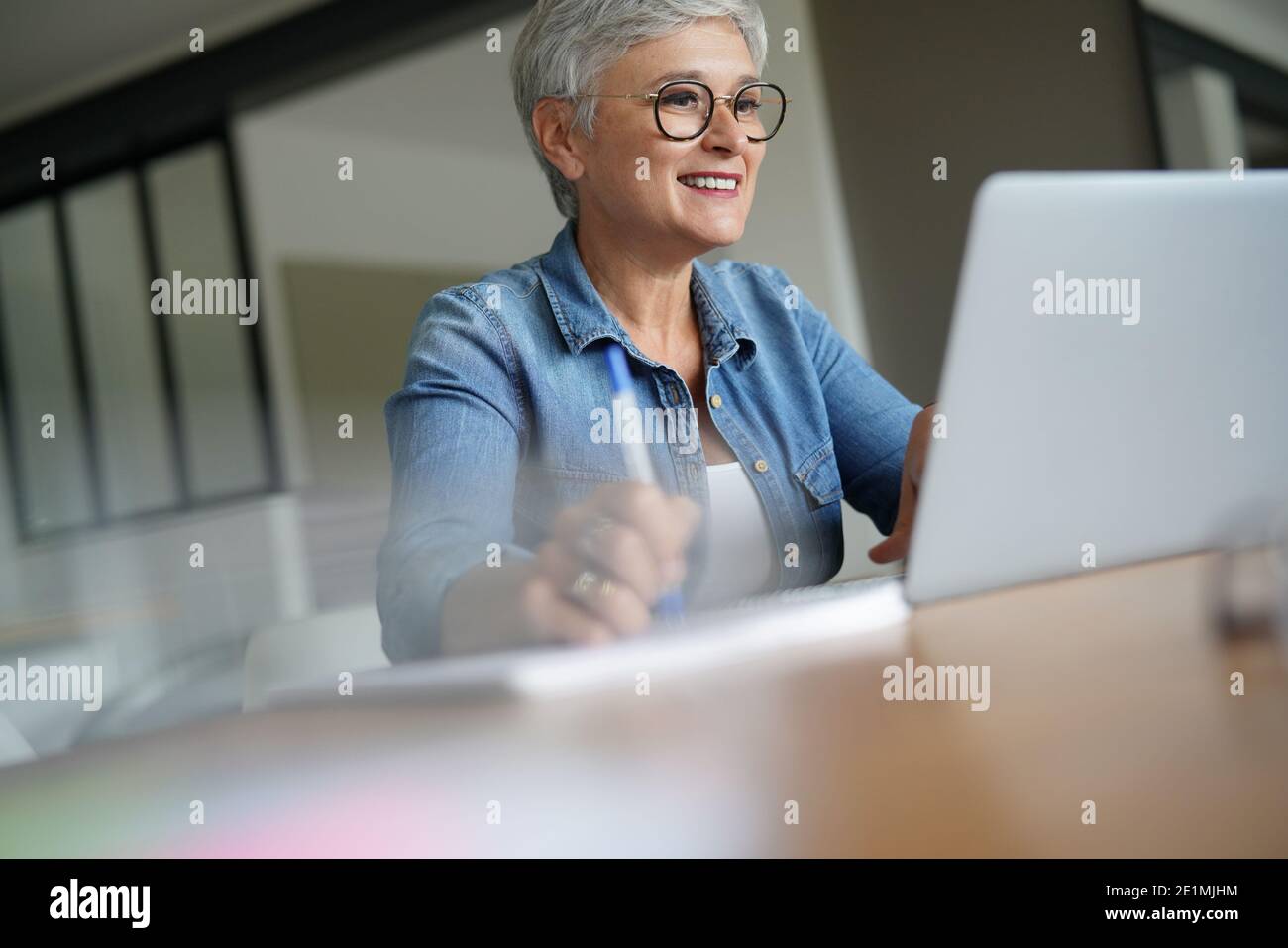 portrait of a beautiful 55 year old woman with white hair working from home Stock Photo
