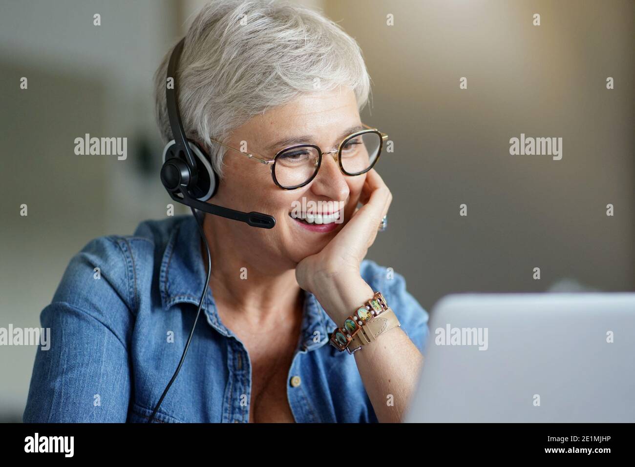 Mature woman with grey short hair working from home during pandemia Stock Photo