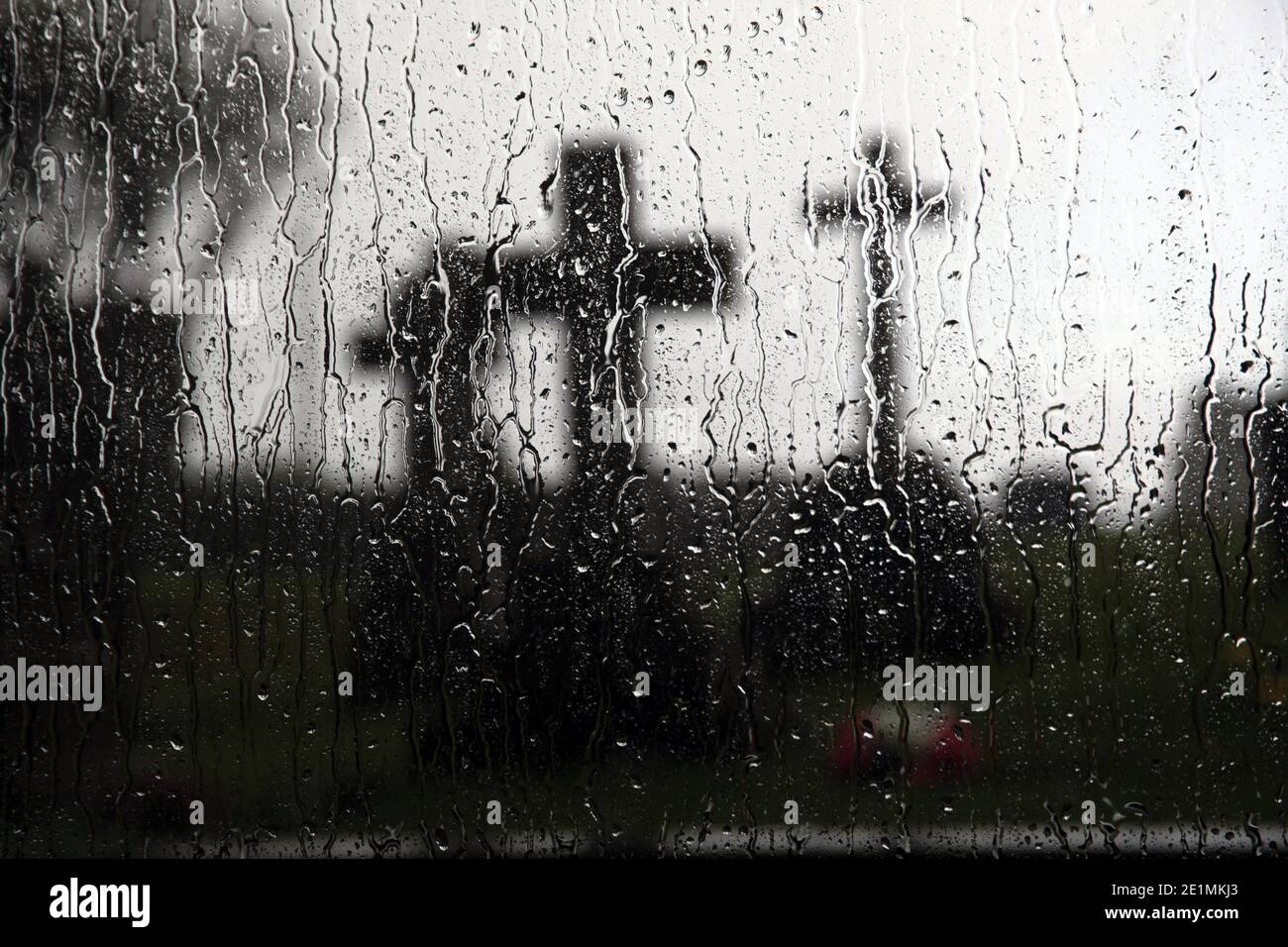Christian crosses in a grave yard viewed through a raindrop covered window . Melancholy scene Stock Photo