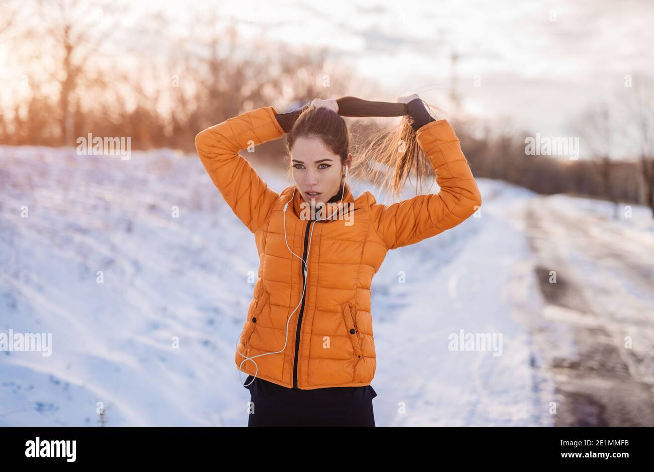 Beautiful young woman preparing for training. Snowy mountain morning fitness. Stock Photo