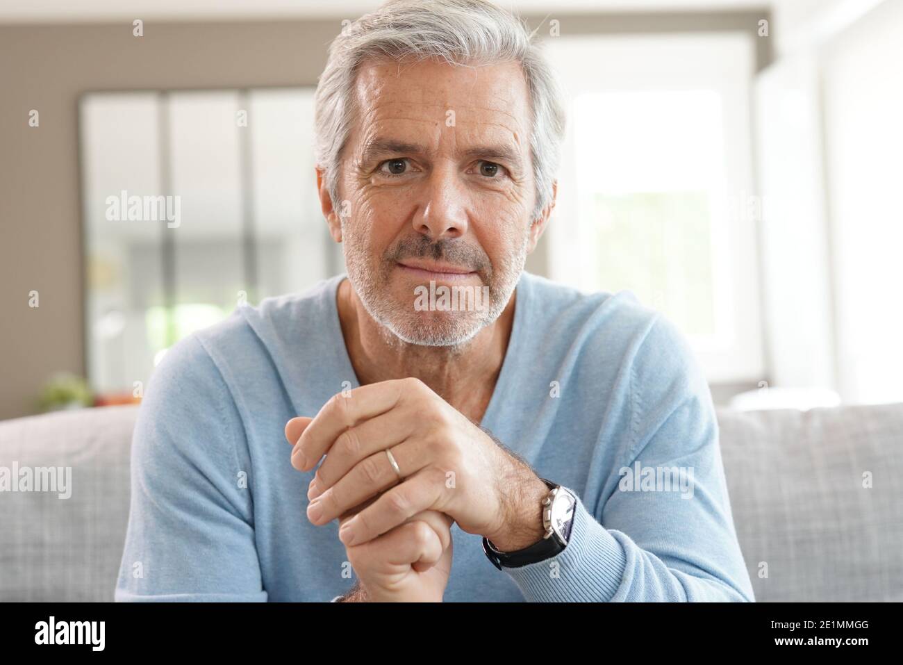 Portrait of attractive senior man with blue sweater relaxing at home Stock Photo