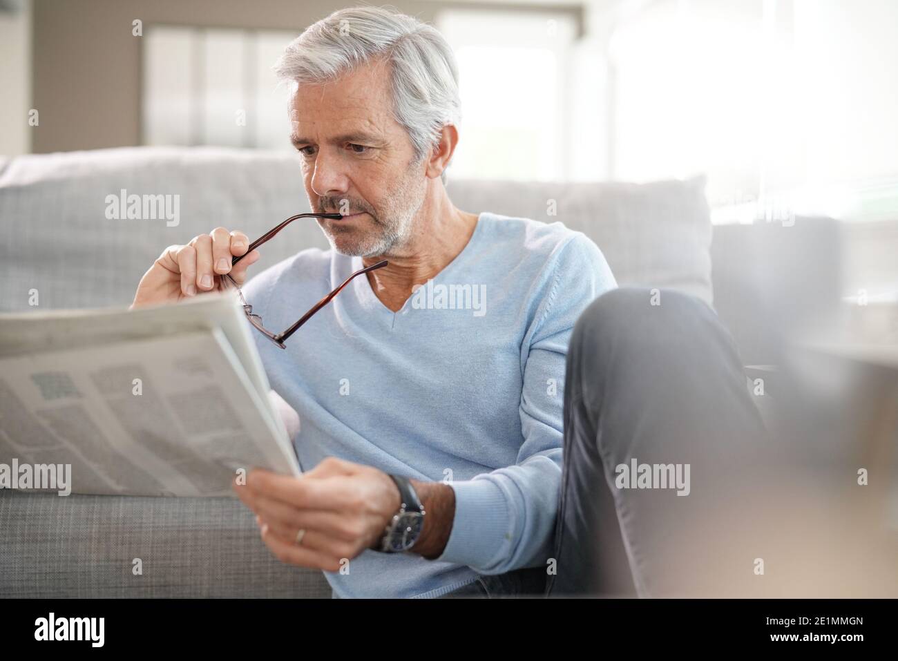 Attractive senior man relaxing at home reading newspaper Stock Photo