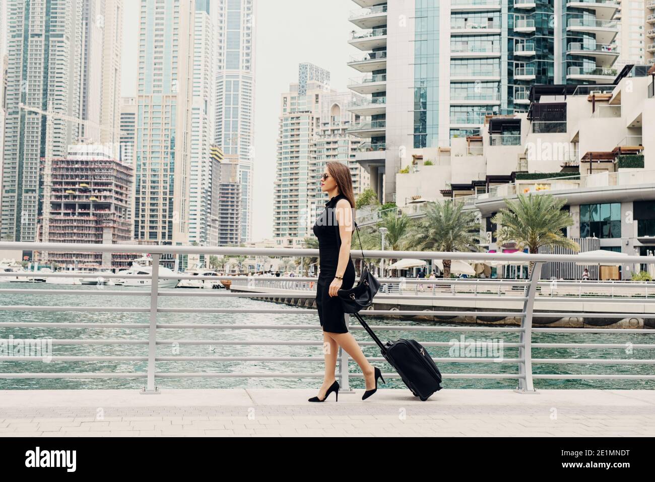 Young modern confident business woman pulling a suitcase in a Dubai