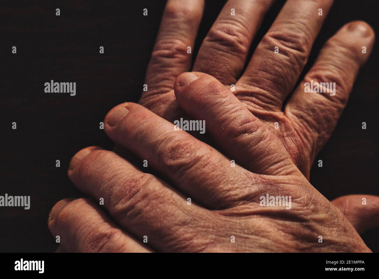 Wrinkled hands of old man on top of each other. Close up. High angle view. Stock Photo