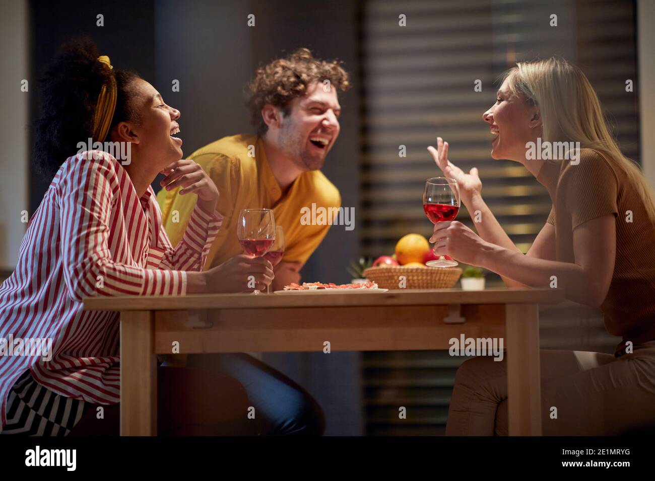 Group of three happy friends having home gathering together Stock Photo