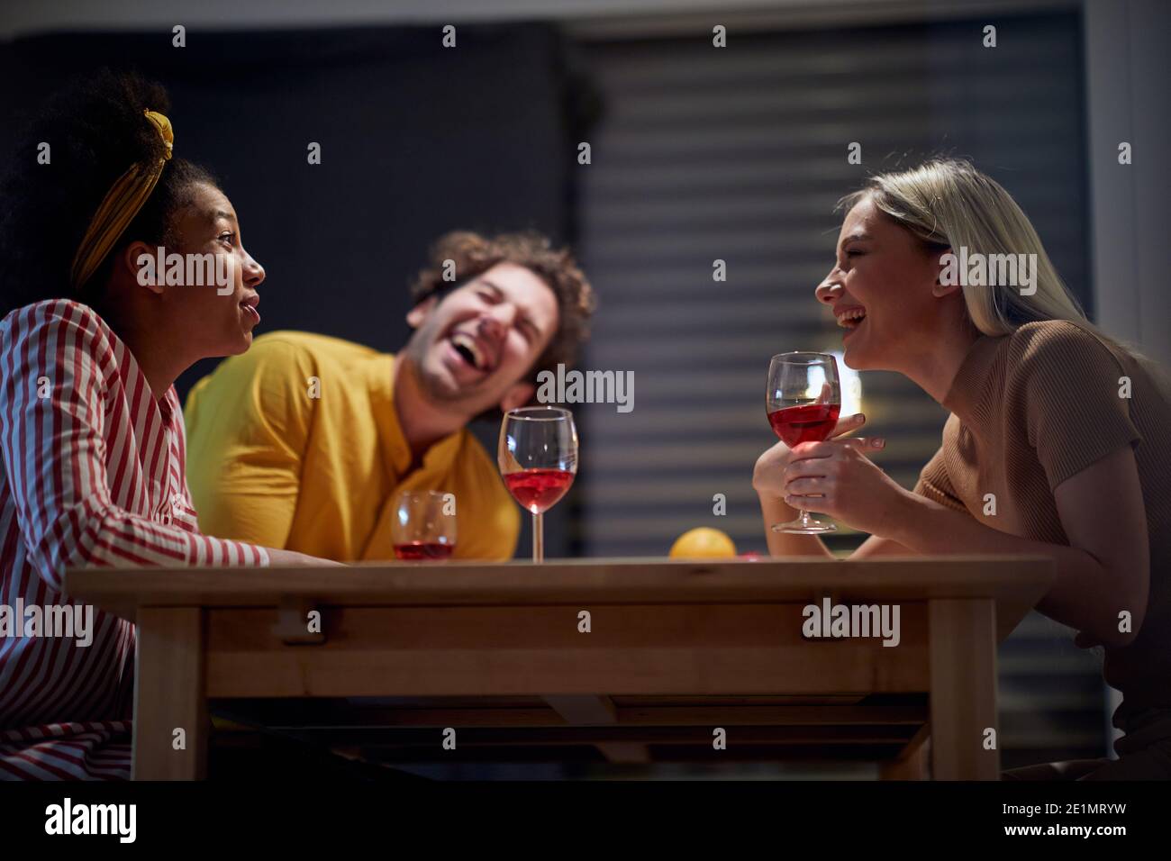 Friends having fun while drinking wine in a cheerful atmosphere at the kitchen. Dinner, friendship, together, home Stock Photo