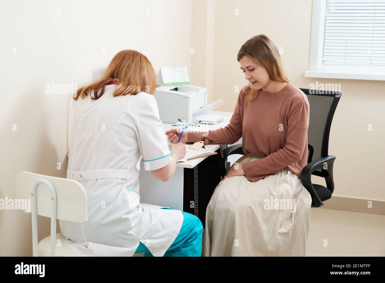 Nurse measures the height of young woman at the doctor office Stock Photo