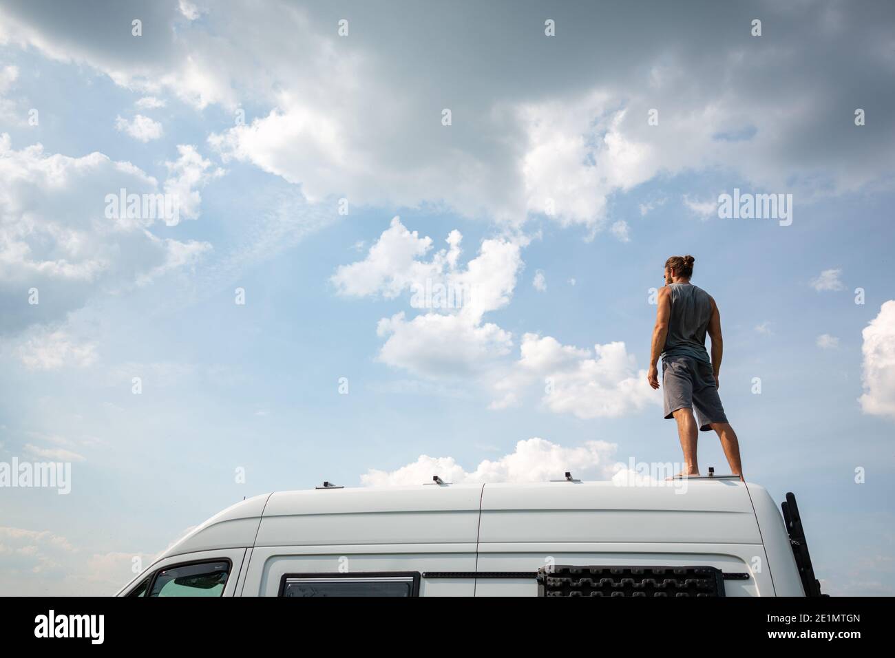 Man standing on top of his camper van Stock Photo