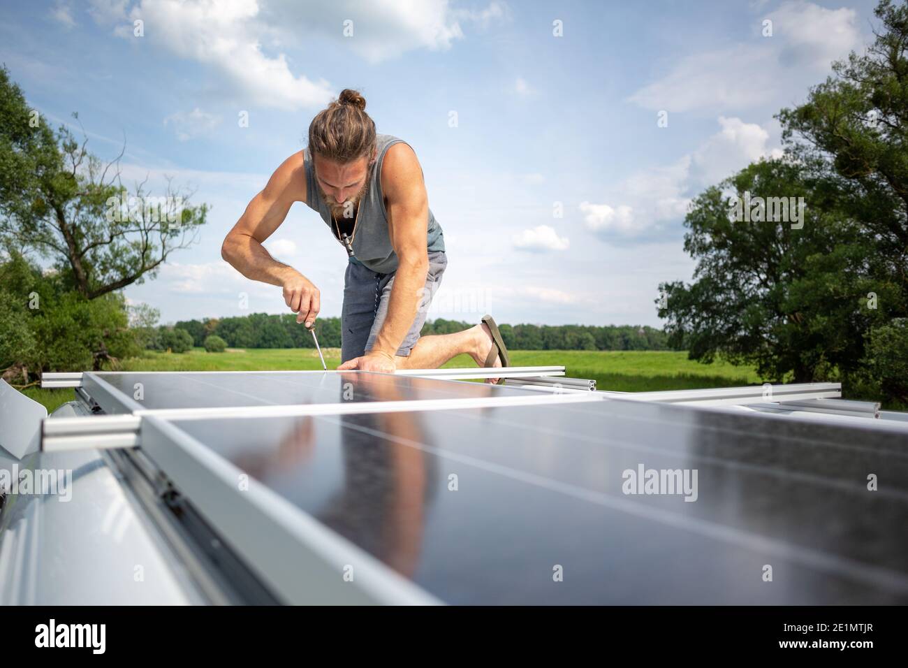 Man working on a solar panel on top of a caravan Stock Photo