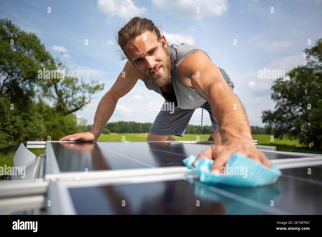Man wiping a solar panel on the roof of a caravan Stock Photo