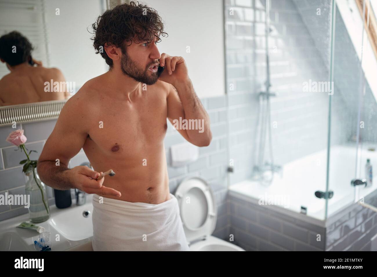 Angry topless man fighting while brushing teeth in the bathroom Stock Photo