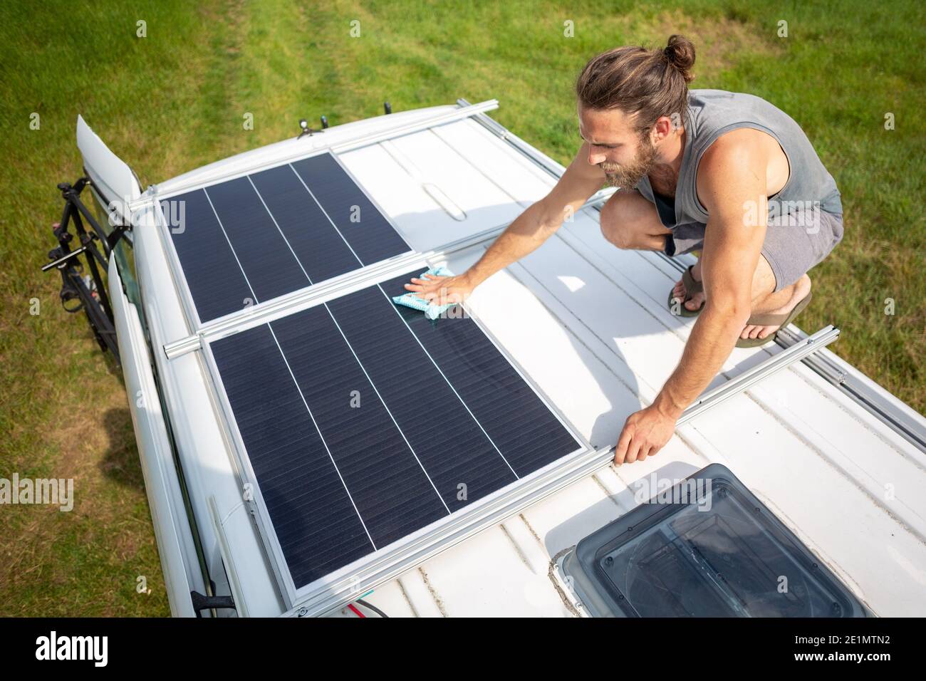 Man cleaning a solar panel on the roof of a camper van Stock Photo