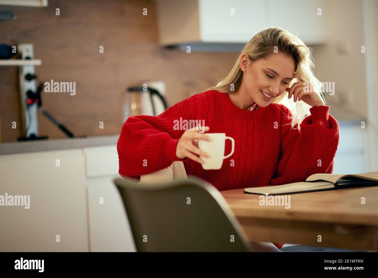 A young girl having a cigarette and a coffee while studies on a beautiful morning at the kitchen. Routine, student, morning Stock Photo