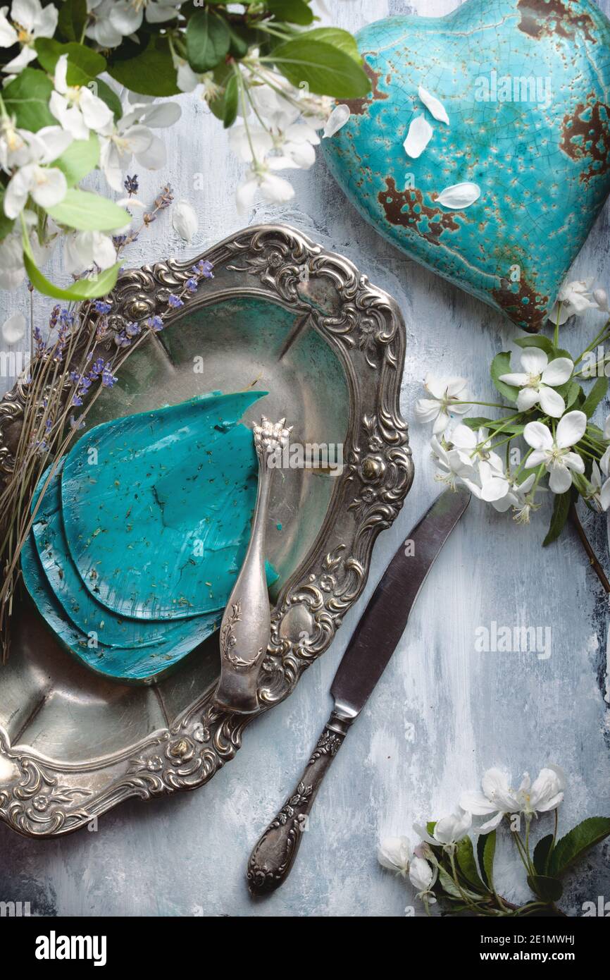 flatlay food background - empty wooden table with blue cheese pieces, white flowers and silver antique dishware Stock Photo