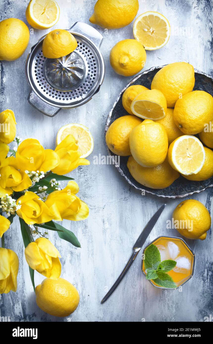bright flatlay food background - empty wooden board with lots of lemons, yellow flowers, squeezer and knife, with copy space for text Stock Photo
