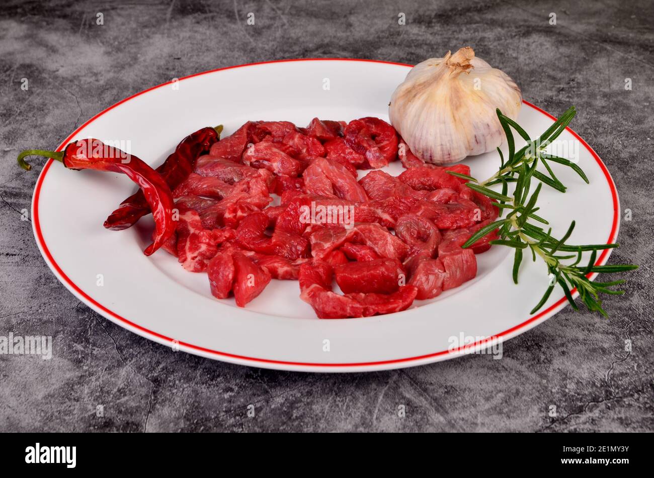 Raw beef meat cut into thin strips for beef Stroganoff on white plate