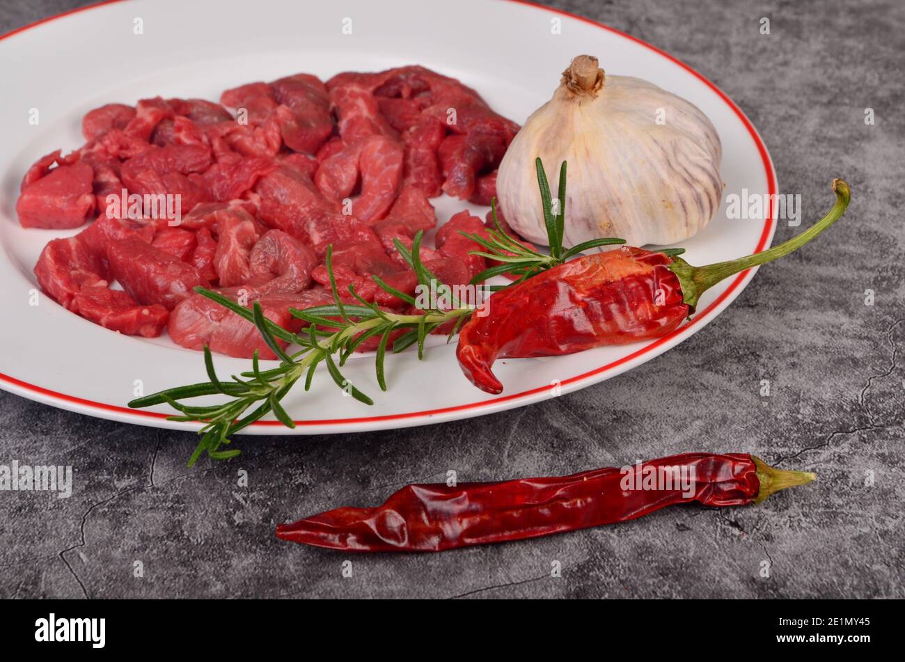 Raw beef meat cut into thin strips for beef Stroganoff on white plate