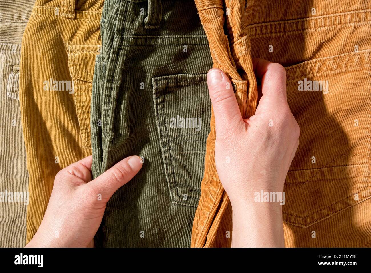 Hands touch the corduroy trousers lying on the counter. Shopping.  Stock Photo