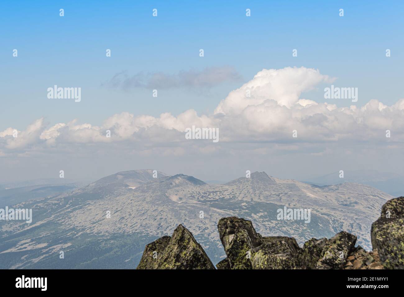 Rocky ridge on horizon under blue cloudy sky. Mountain valley for travel. Adventure travel, tourism and conservation concept. Stock Photo