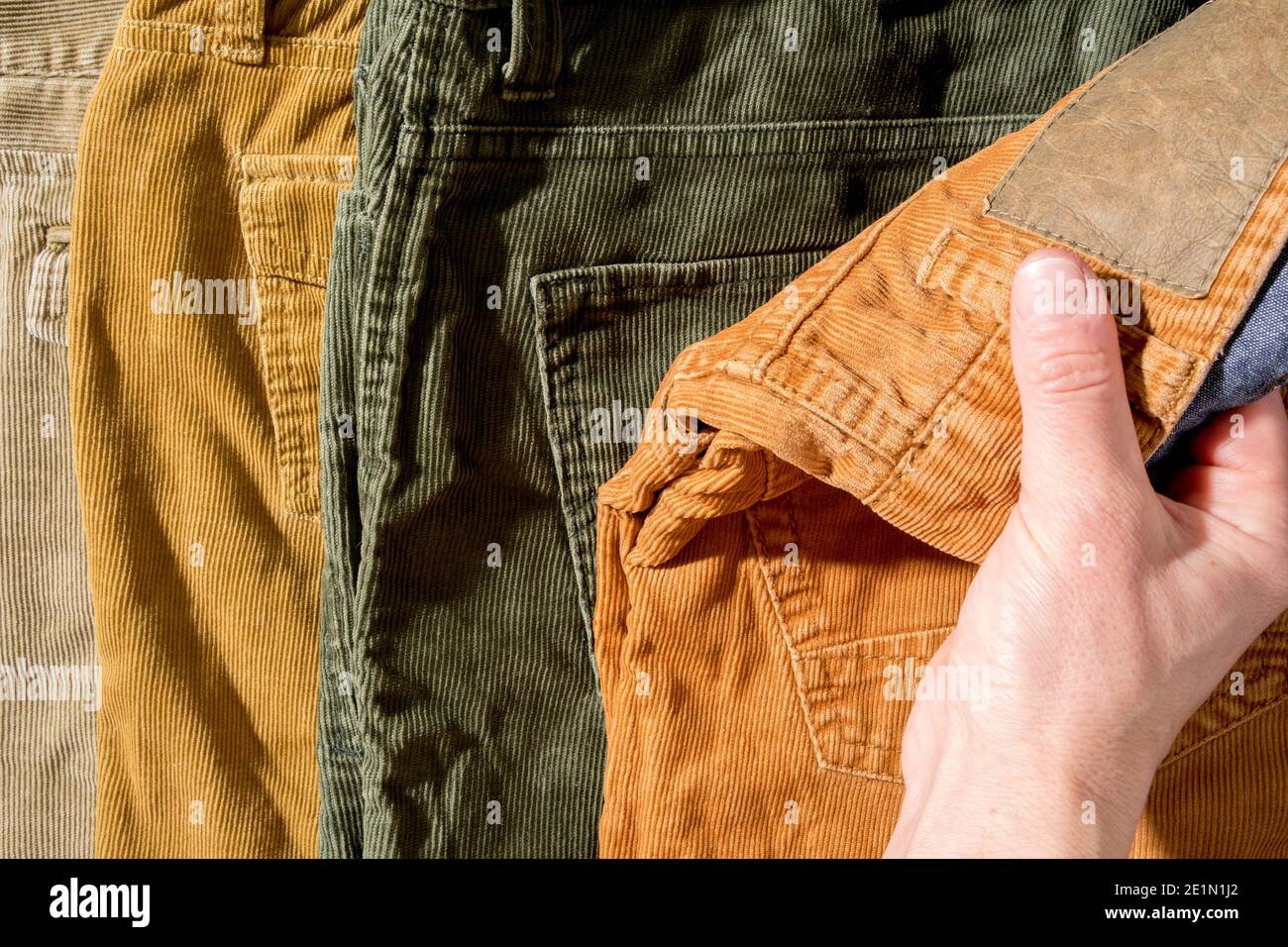 Hand grabs corduroy trousers, on sale. Shopping.  Stock Photo