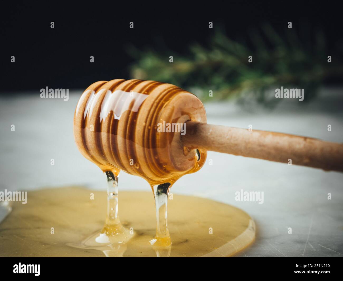 Honey wood dipper is pouring honey. Honey dripping on white marble top