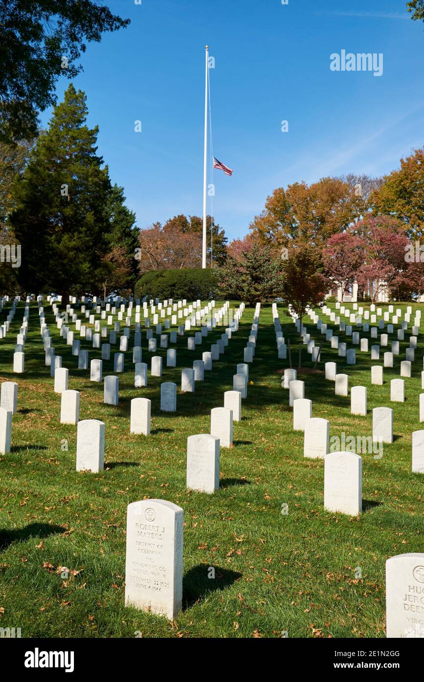 A flag flies at half staff over rows of identical graves at Arlington National Cemetery near