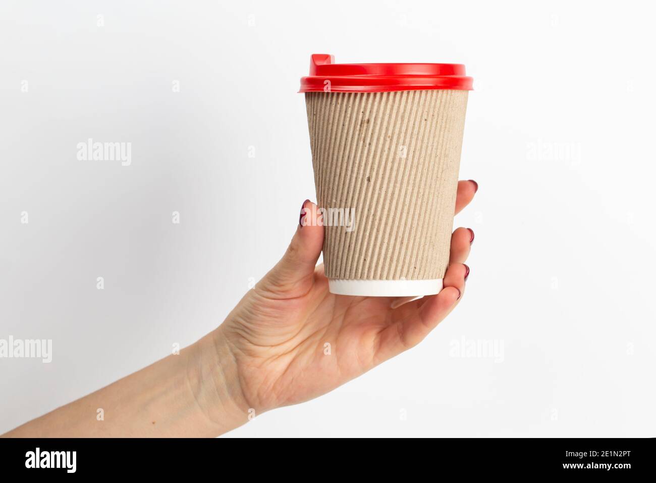 Female hand holding disposable coffee cup brown colour on white