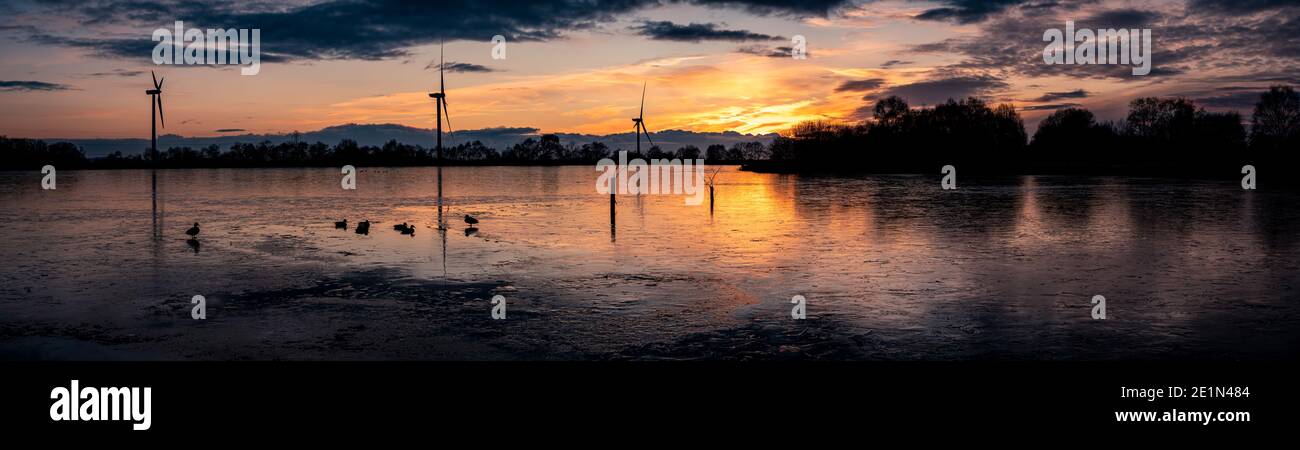 Beautiful sunset at Pen-y-fan pond with the pond completely frozen over with turbines in background, located in Blackwood,Wales UK Stock Photo