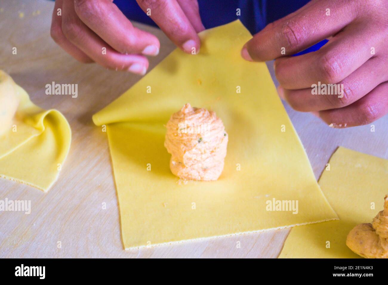 hand of the Italian housewife prepares egg pasta, ravioli and tortelli, stuffed with salmon stuffing, for the party lunch. Stock Photo