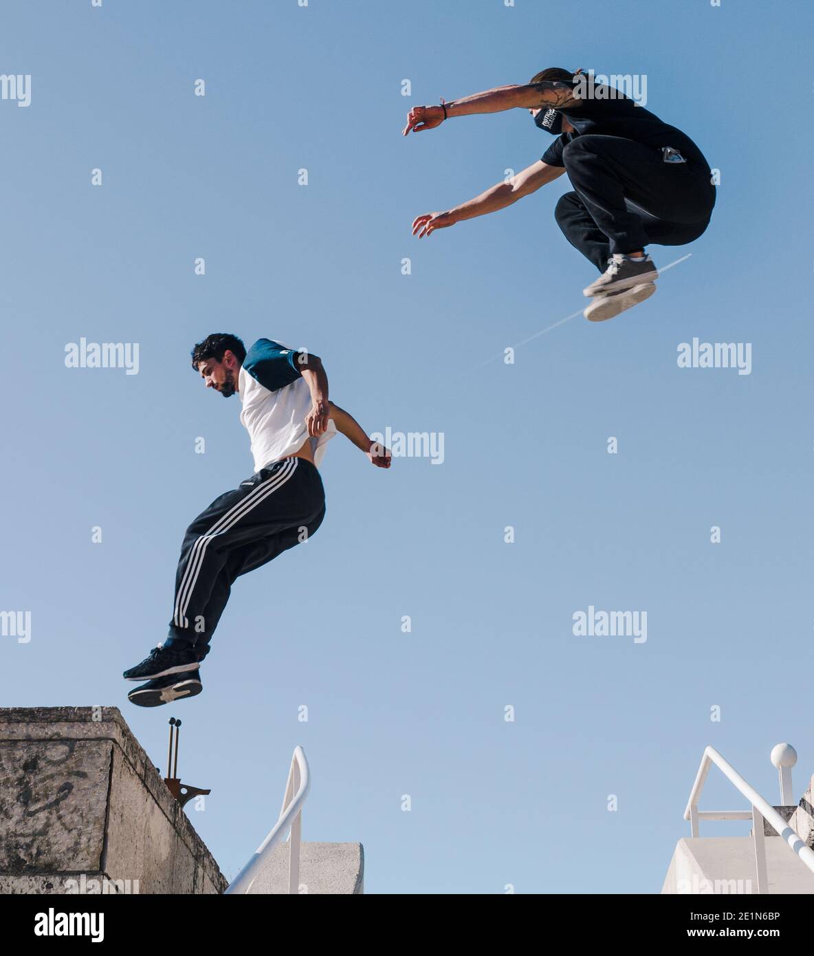 Two young man flying over some urban stairs I jump high above the clear sky Stock Photo