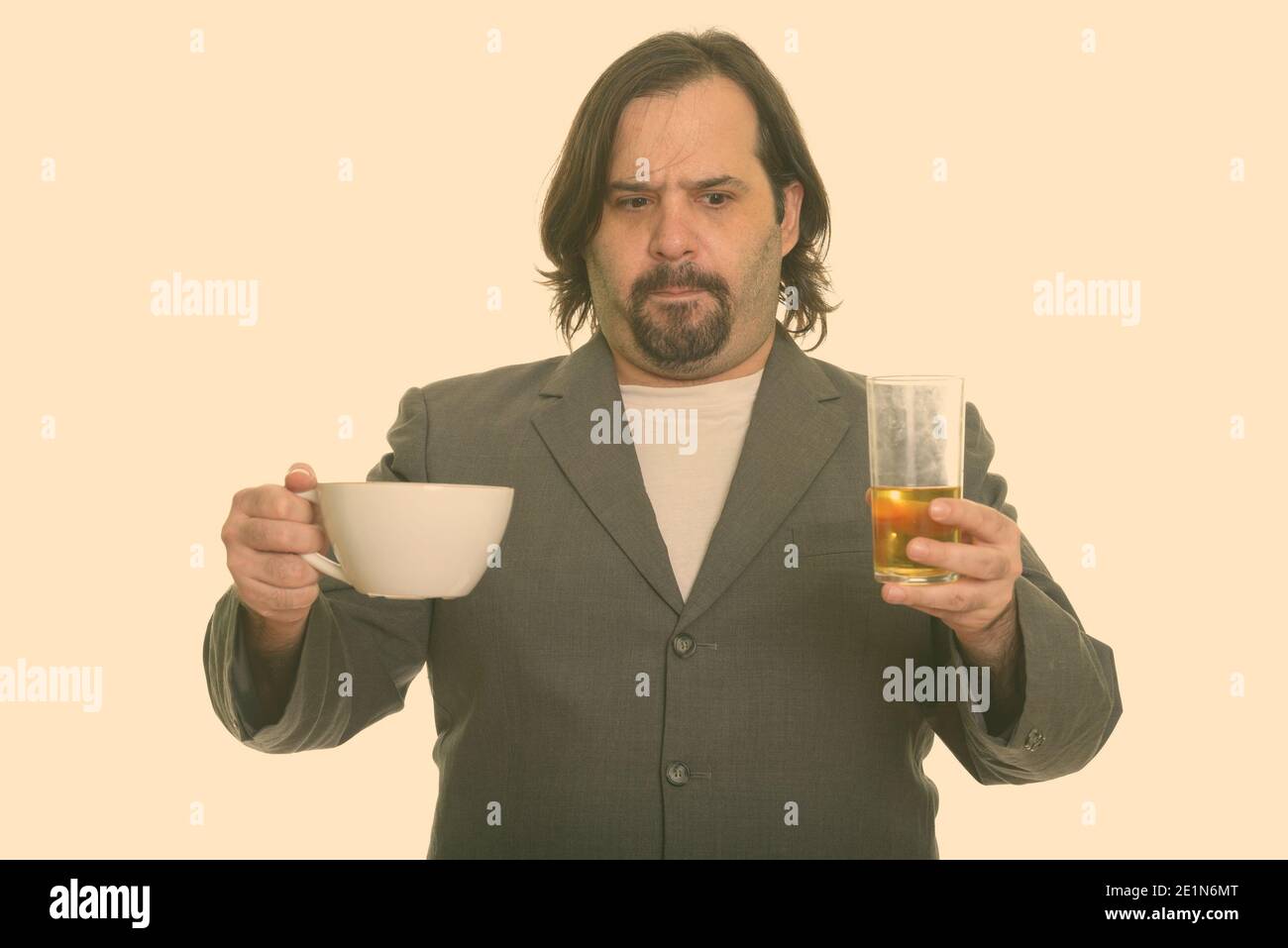 Fat Caucasian businessman choosing between coffee and beer Stock Photo