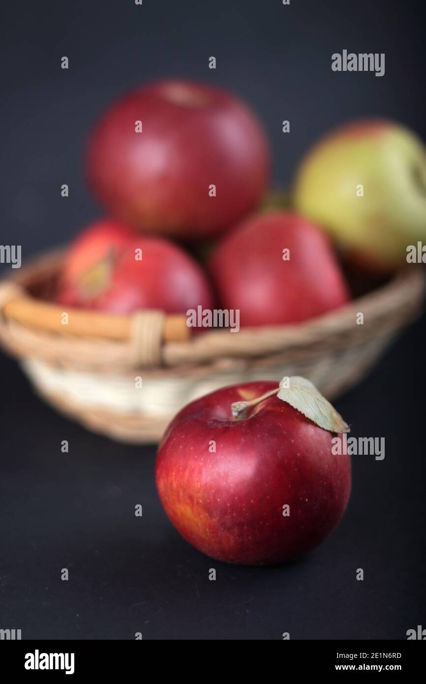 a pile of apples in a basket isolated on black background vertical