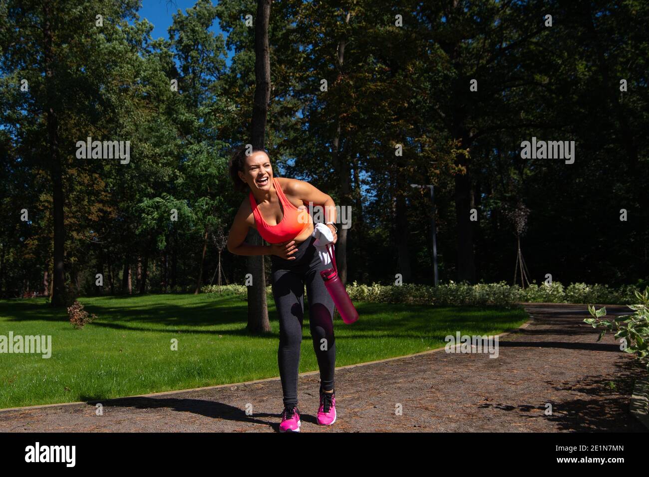 Runner woman suffering from stomach pain after running outdoors. concept of sport injuries Stock