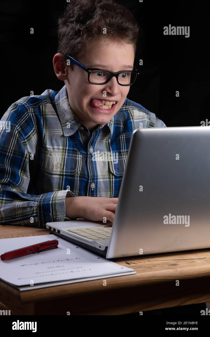Boy funny on PC with tongue out on laptop Stock Photo