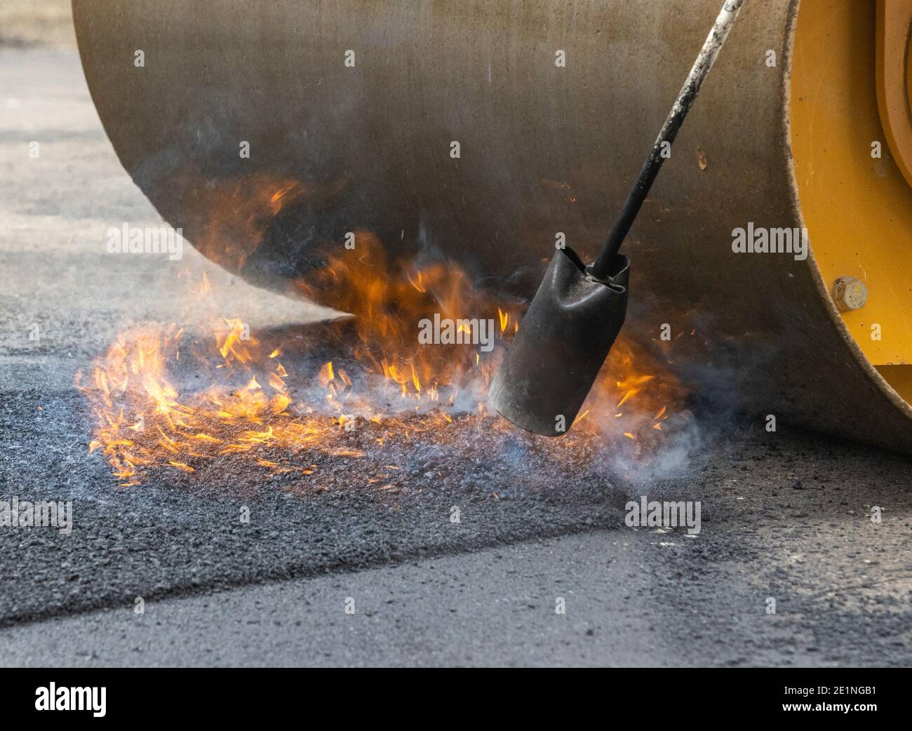 Flame and Steam Rising as asphalt Seam is Sealed and Rolled Smooth Stock Photo