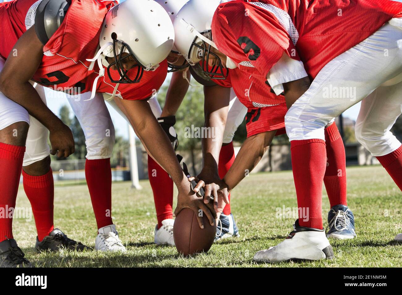 Photo of Football Players in Huddle Holding Football Stock Photo